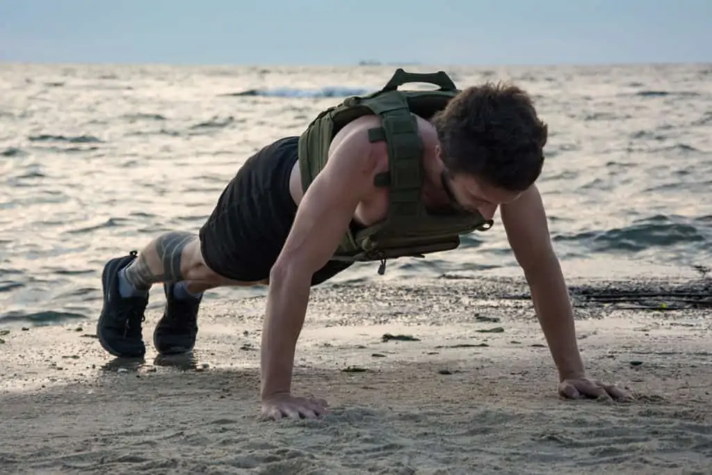 Doing pushups in a weighted vest on the beach