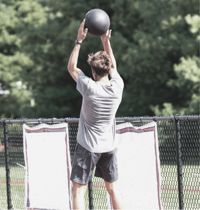 Guy outside smashing a slam ball for conditioning