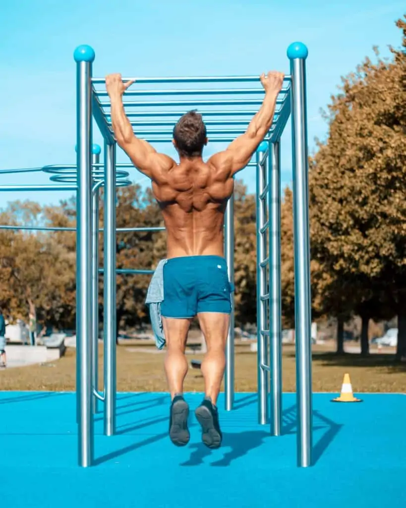 Guy hanging on monkey bars in an outdoor fitness park